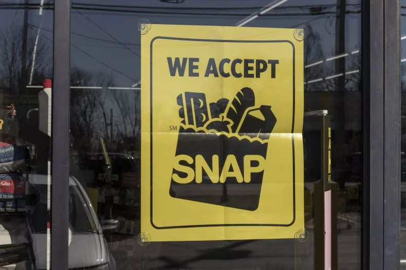 A yellow sign hanging in a window that says "We accept SNAP"