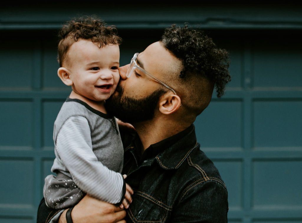 A father holds a smiling baby kisses his cheek